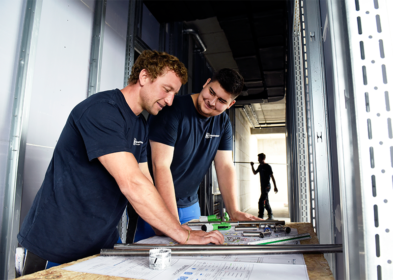 Zwei Mitarbeiter mit Kratschmayer T-Shirts besprechen auf einer Baustelle die technische Zeichnung