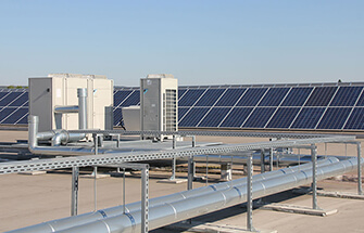 Lüftungstechnik auf dem Dach mit Photovoltaikanlage im Hintergrund